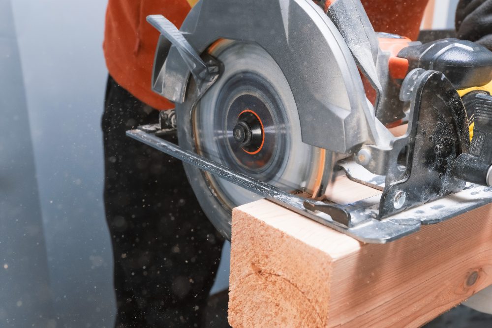 Circular saw cutting through wooden board with dust spray visible