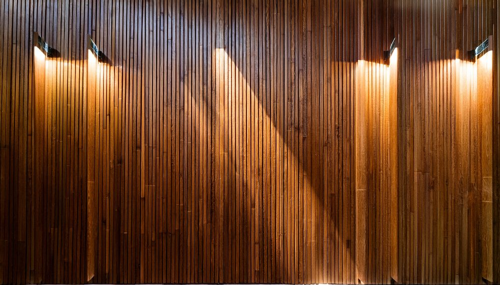 Wooden vertical slat wall with warm uplighting creating striped shadow patterns